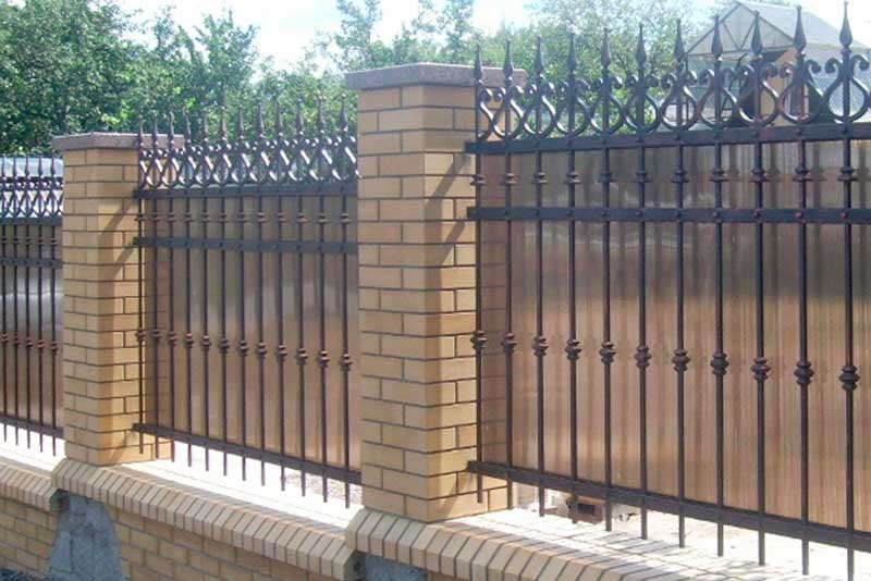 Кованый забор с поликарбонатом и кирпичными столбами